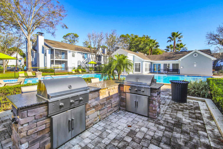 outdoor grill space with two gas grills adjacent the pool